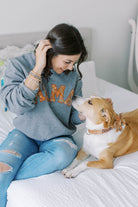 a model wearing Dog Mama Sweatshirt with her dog wearing a matching embroidered collar. Dog Mom sweatshirt with matching accessories.
