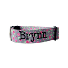 Gray dog collar with pink rose and green leaf pattern and 'Brynn' printed on it against a white background. Floral embroidered dog collar by Duke & Fox.